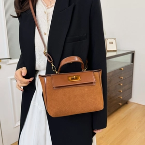 Caramel brown suede leather handbag with metal turn-lock closure shown on a model