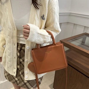 Brown leather crossbody bag with small pouch and fashion text on a stylish model