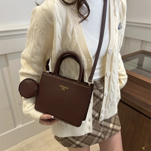 Dark brown leather handbag with gold lettering and a round coin purse on a model