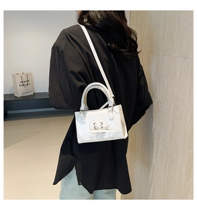 Dettaglio della mini borsa bianca a tracolla con intaglio a cuore e fiocco decorativo