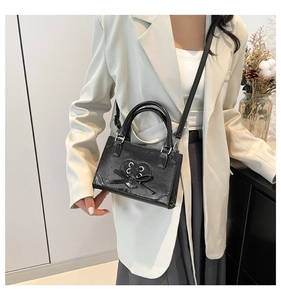 Detail van zwarte glanzende crossbodytas met hartvormige uitsnede en vetersluiting lint