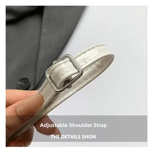 Detail van verstelbare witte lederen schouderriem met zilveren metalen gesp op handtas