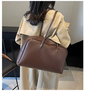 Detailed view of deep brown pebbled leather tote bag worn by model in a minimalist room