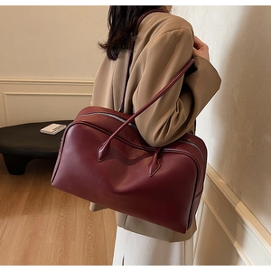 Detail of burgundy pebbled leather tote bag with sturdy handles and top zipper closure