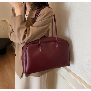 Detail of burgundy textured leather tote bag showing spacious design and slim shoulder straps