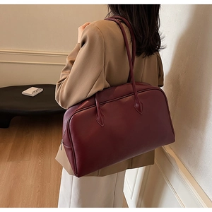 Close-up of deep burgundy leather texture and sturdy double handles on large tote bag