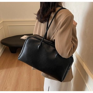 Side view of large black leather tote bag worn by model, showing capacity and minimalist style