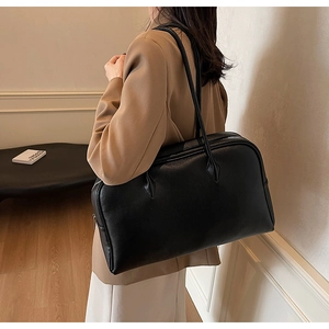 Detail showing the textured black leather surface and spacious design of the tote bag