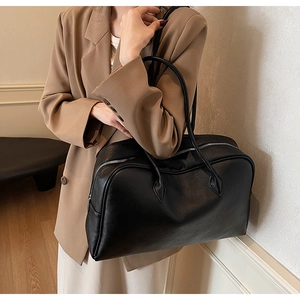 Close-up of black leather Boston bag with pebble grain texture and twin shoulder straps
