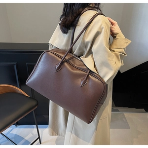 Detailed close-up of dark brown lychee grain leather and metal zipper on the tote bag