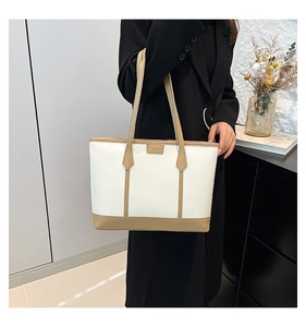 Detail of a chic cream and khaki faux leather tote bag worn with a black blazer