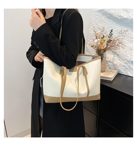 Detail of minimalist two-tone leather tote bag with khaki trim on creamy white body