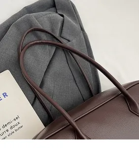 Detailed close-up of dark brown lychee grain leather tote bag with smooth long straps