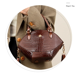 Détail du sac à main marron foncé aspect crocodile avec élégante boucle fleur dorée