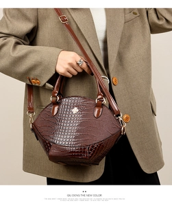 Détail d'un sac à main marron foncé à texture crocodile avec emblème floral métallique