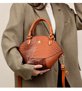 Détail du sac orange motif crocodile avec logo trèfle doré et bandoulière réglable