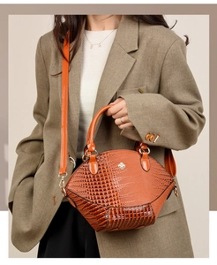 Détail de la texture crocodile orange et du logo trèfle sur le sac à main pour femme