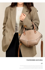 Détail d'un sac à main beige à motif crocodile avec boucle abeille dorée et bandoulière
