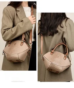 Détail macro du sac à main beige gaufré crocodile avec un emblème floral doré