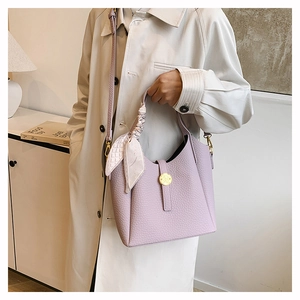 Detail of light purple bucket bag with lychee texture and silk scarf handle decoration