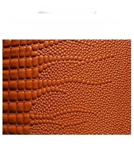 Vue macro détaillée de la texture du cuir gaufré crocodile orange au fini brillant