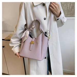 Close-up of lilac bucket bag featuring lychee texture and silk scarf handle detail