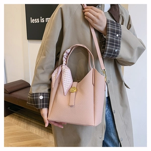 Detail view of pink lychee leather bucket bag with silk scarf handle and gold metal lock