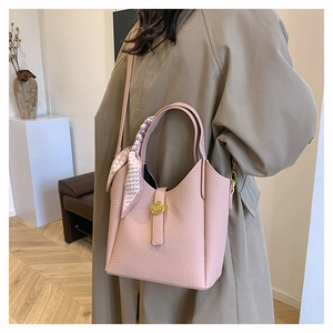 Close-up of pink litchi leather bucket bag with gold ring hardware and silk scarf