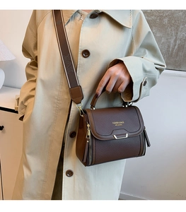 Detail of dark brown leather handbag with jacquard strap and golden zipper accents