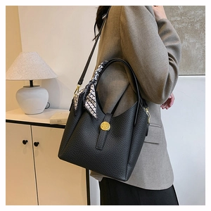 Detail of black lychee grain leather bucket bag with silk scarf and gold metal buckle