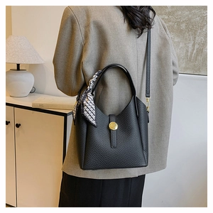 Detail of black pebbled leather bucket bag with geometric silk scarf and gold lock