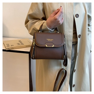 Detail of dark brown lychee leather handbag with golden buckle and designer wide strap