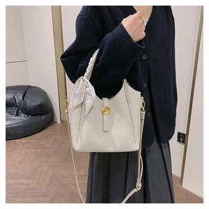 Detail of off-white lychee leather bucket bag with silk scarf handle and gold buckle