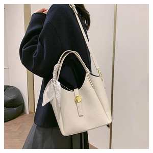 Detail of cream leather bucket bag with litchi texture, silk scarf and gold logo buckle