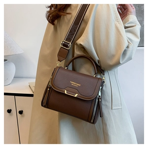 Close-up of brown litchi pattern leather bag with wide printed strap and golden hardware