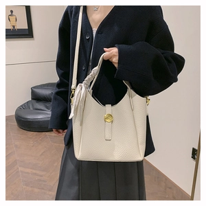 Detail of cream bucket bag with lychee leather texture and silk scarf handle detail
