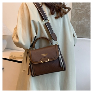 Detail of dark brown lychee pattern handbag with gold clasp and wide strap