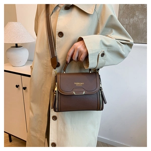 Brown lychee leather tote with gold hardware and wide print strap on beige coat