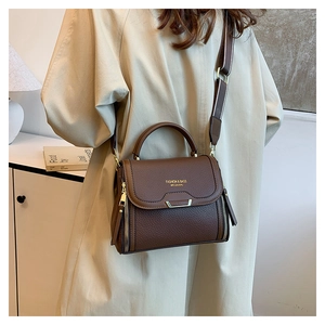 Detail of deep brown litchi pattern leather handbag with striped strap and gold metal