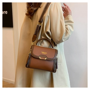 Close-up of brown litchi pattern leather handbag with gold clasp and wide strap