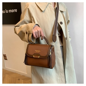 Brown lychee leather handbag with gold trim shown on model in beige trench coat