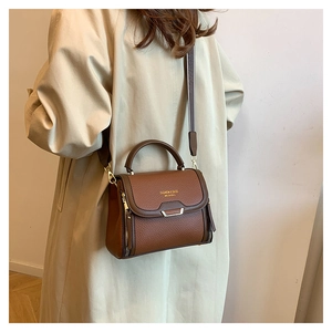 Detail of brown litchi pattern leather handbag with metal buckle and shoulder strap