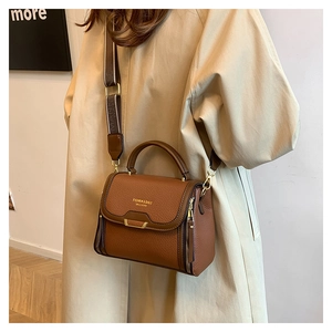 Brown litchi leather bag detail with wide tricolor strap and metal buckle