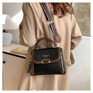 Detail of bicolored crossbody bag with gold U-shape hardware and wide logo strap