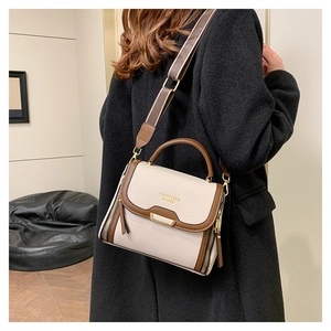Close-up of a two-tone lychee leather handbag with wide shoulder strap worn by a model