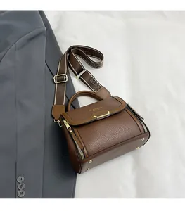 Detail of brown litchi pattern leather bag with wide strap and gold hardware accents