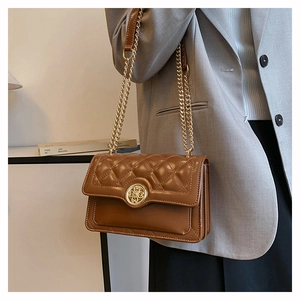 Close-up of brown quilted shoulder bag with gold chain straps and elegant metal buckle