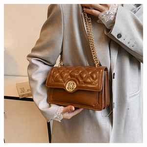 Close-up of brown quilted leather bag featuring a gold floral clasp and metal chain strap