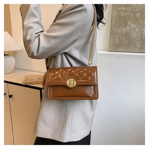 Close-up of brown quilted leather bag with gold circular buckle and elegant chain strap