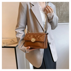 Detailed view of brown quilted chain bag with gold floral buckle on female model